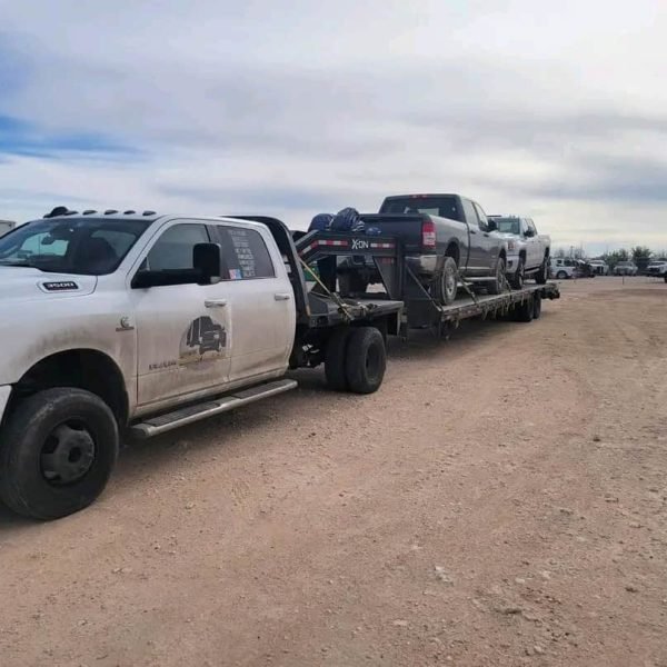 Flatbed truck transporting multiple vehicles for auto shipping.