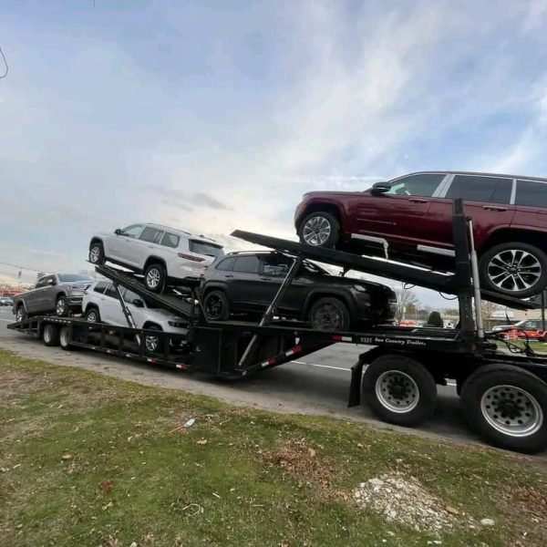 Auto transport truck carrying multiple vehicles on highway.