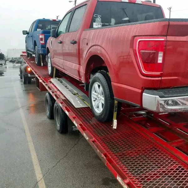 Red pickup truck on car carrier for auto transport service.