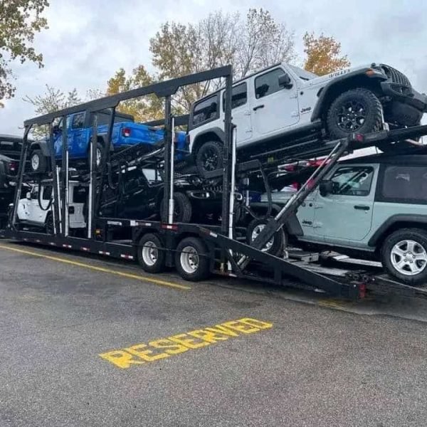 Car carrier transporting multiple vehicles including SUVs and trucks.
