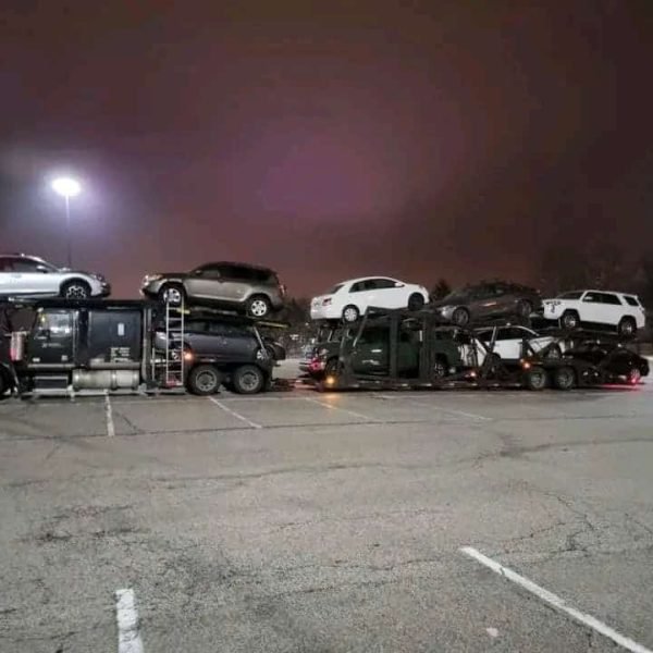 Car carrier truck transporting multiple vehicles at night.