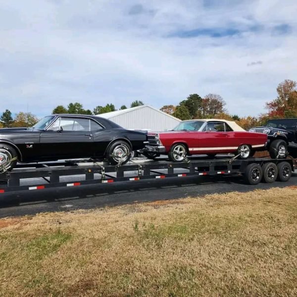 Multiple classic cars loaded on a flatbed trailer for auto transport.