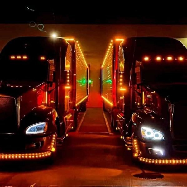 Night view of illuminated car carriers with LED lights for auto transport.